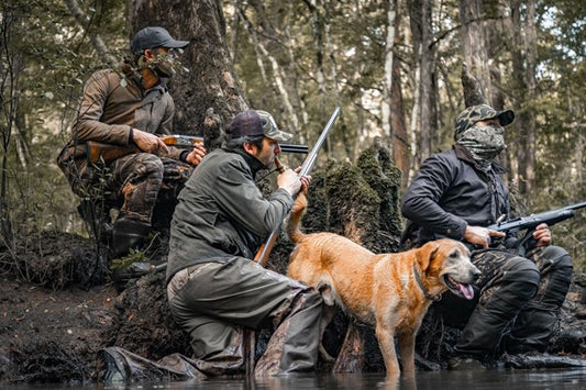 Hunters in camo gear with hunting dog and bird call